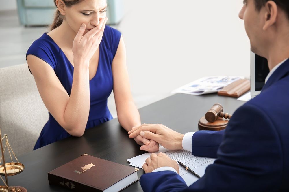 Crying woman consulting lawyer for wrongful death lawsuit.
